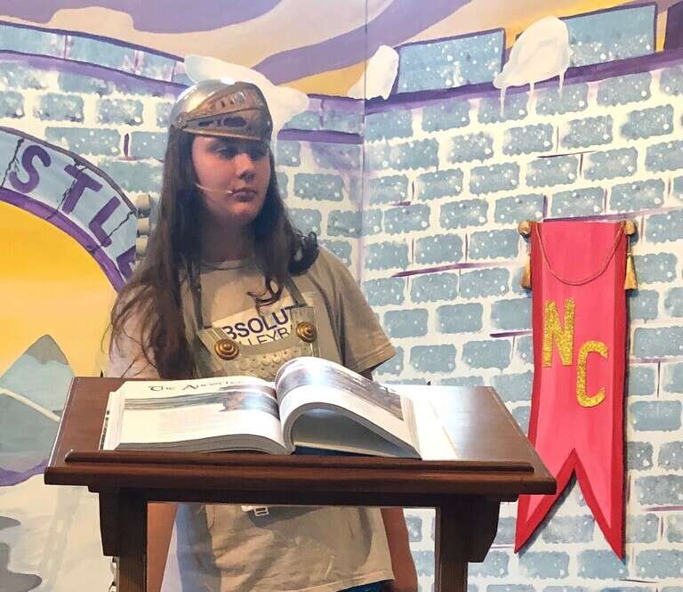 A teenager reading from podium at VBS